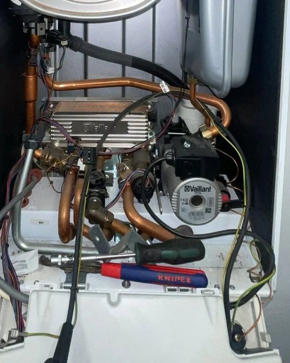 Druk cv-ketel: de koperen leidingen en de drukmeter onder een cv-ketel