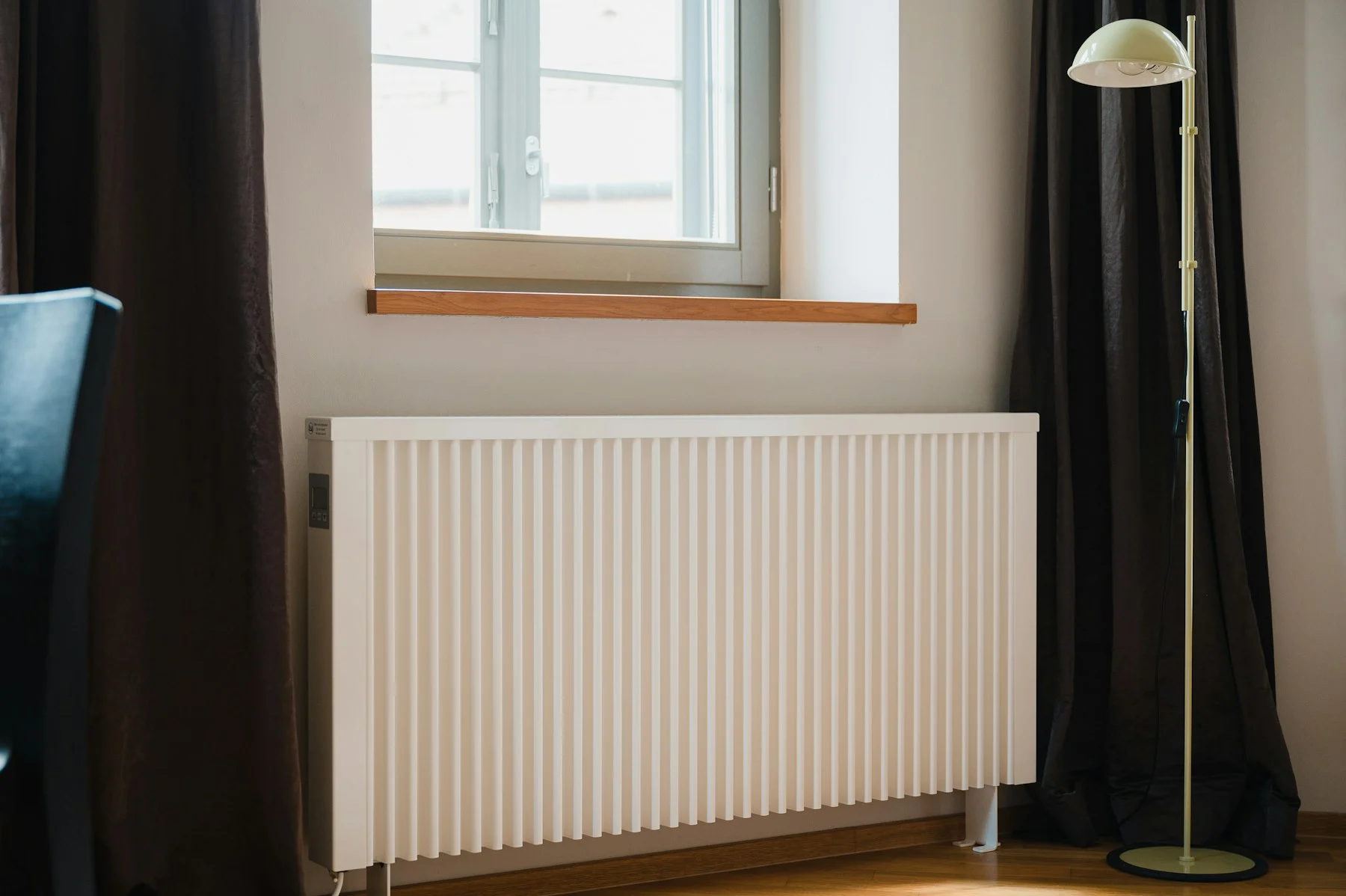 Radiator ontluchten: een radiator onder een raam, met de ontluchtingsnippel bovenaan